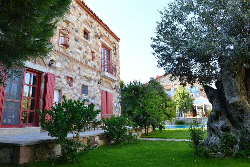 ein Gebäude mit roten Fenstern und einem Baum im Hof in der Unterkunft Alacati Zeytin Konak Hotel in Alacati