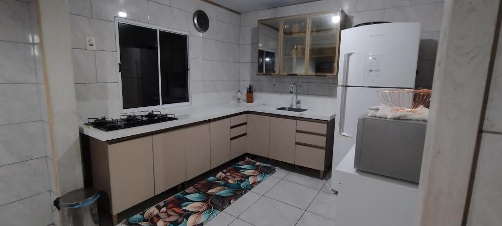 eine weiße Küche mit Spüle und Kühlschrank in der Unterkunft Casa em Tramandaí in Tramandaí