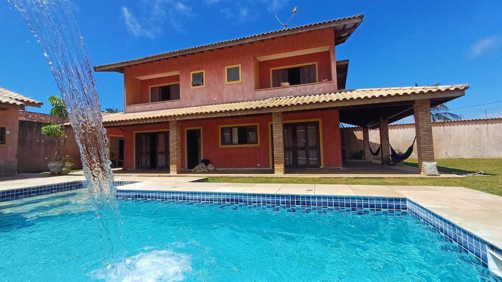 a house with a swimming pool in front of a house at Casa magnífica na praia in Mongaguá