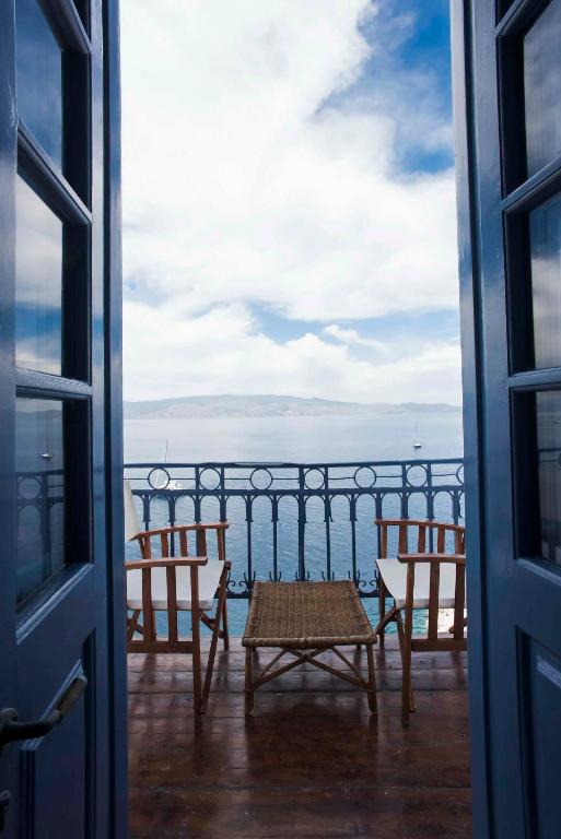 a table and chairs on a balcony overlooking the ocean at Theodora's House in Hydra