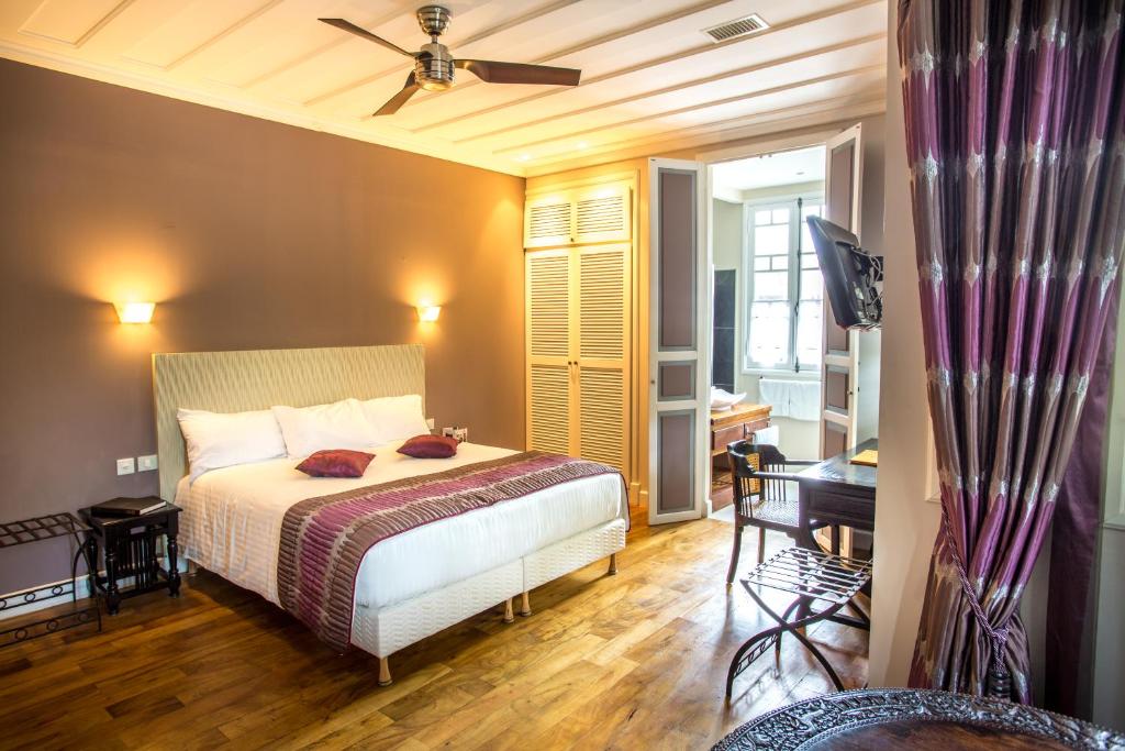 a bedroom with a bed and a ceiling fan at Villa Angélique - Hôtel classé Monument Historique in Saint-Denis