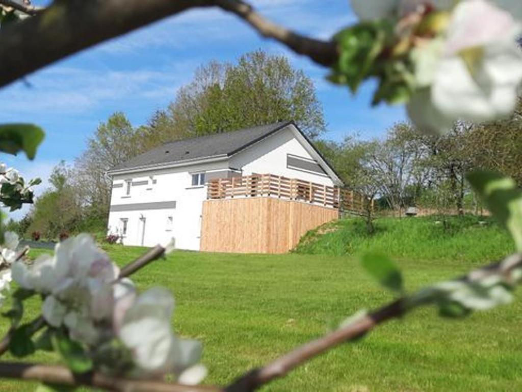 Ein weißes Haus auf einem Feld mit einem Zaun in der Unterkunft Grande maison 10 pers. avec bain nordique et jeux près des Vosges - FR-1-589-773 in Frémifontaine