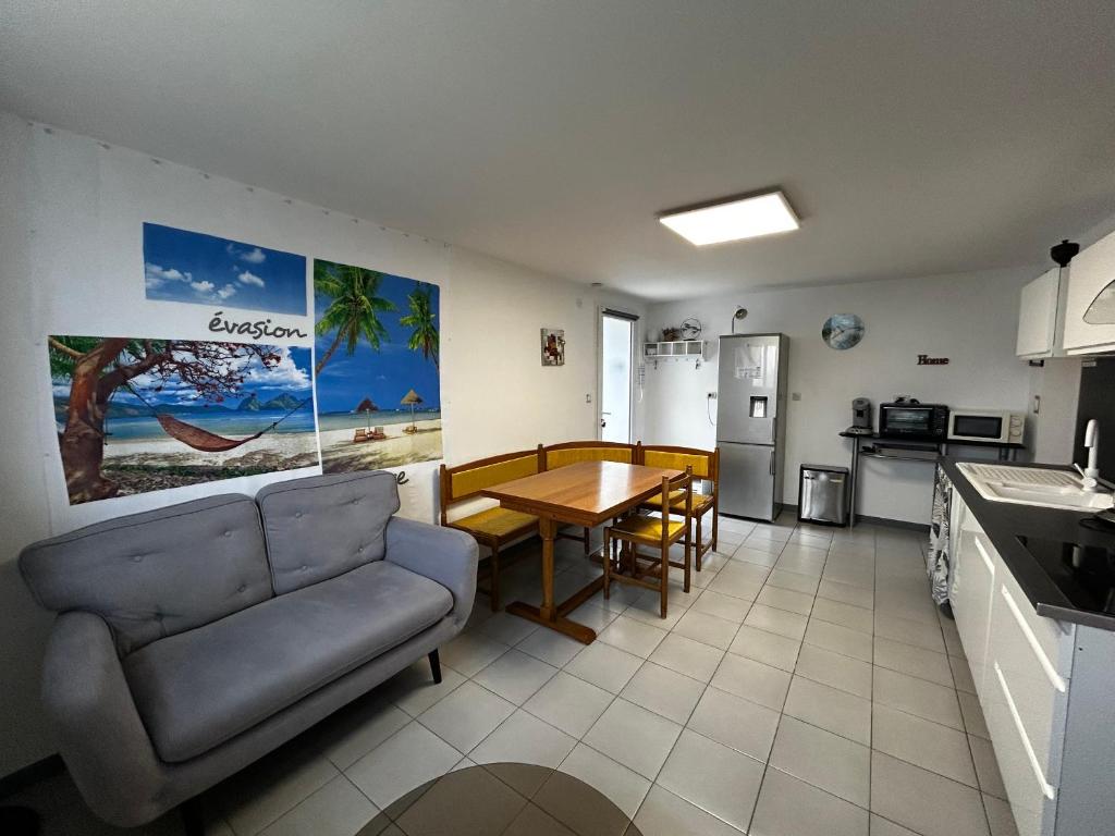 Una cocina y una sala de estar con un sofá y una mesa. en T2 avec jardin, terrasse et Wifi à 1km des Thermes - FR-1-541-156, en La Roche-Posay