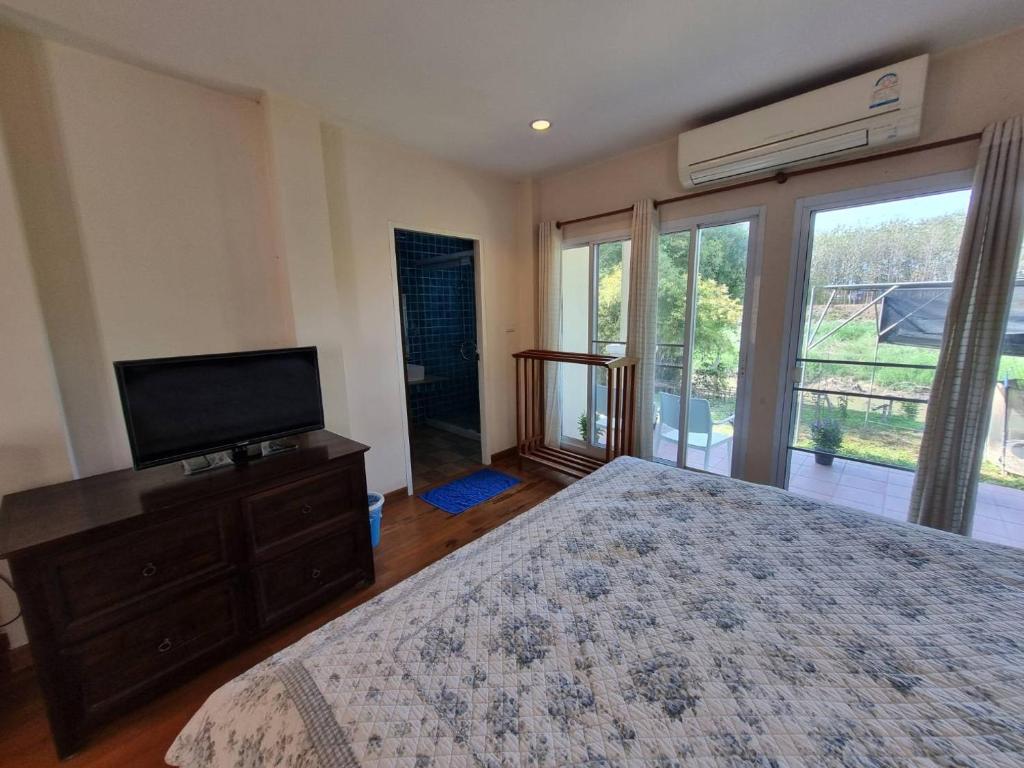 a bedroom with a bed and a flat screen tv at บ้านชยชิโต Chayachito Home Stay in Ban Mo