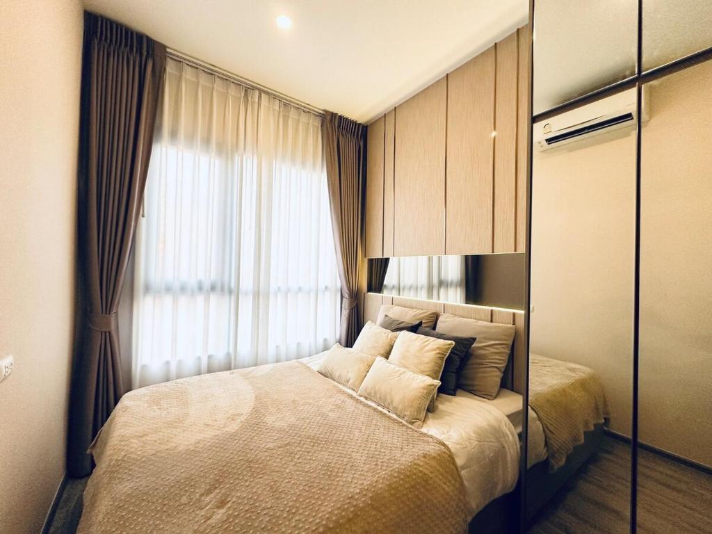 a bedroom with a bed with pillows and a window at Modern condo nr BTS ONNUT WIFI with workroom in Bangkok