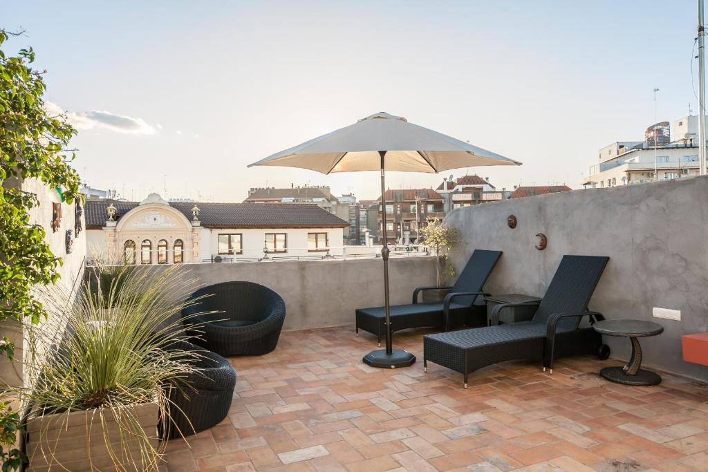 eine Terrasse mit 2 Stühlen und einem Sonnenschirm in der Unterkunft SevillaHome- Ave Cesar in Sevilla