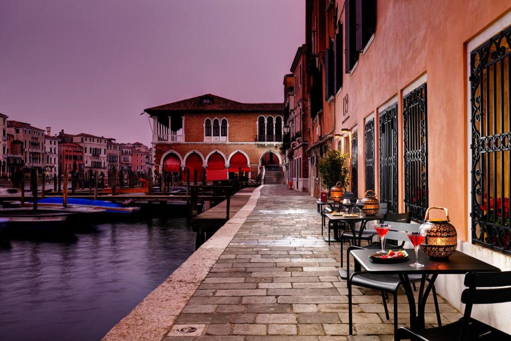 een kanaal met tafels en stoelen naast een gebouw bij Hotel L'Orologio - WTB Hotels in Venetië