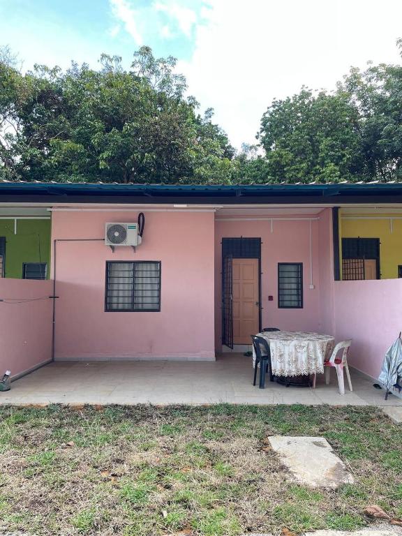 a pink and yellow house with a table on a patio at D'Padang KB Homestay in Kuala Berang