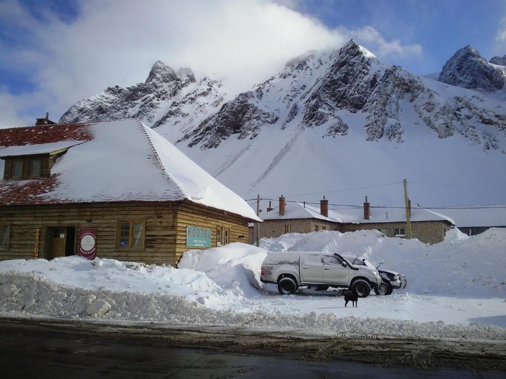 a car parked in front of a snow covered house at Portezuelo del Viento - Hostel de Montaña in Las Cuevas