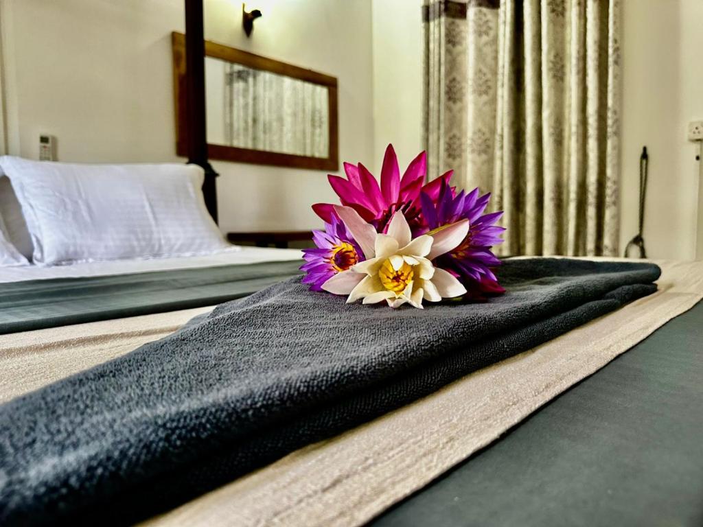 a purple and white flower sitting on top of a bed at Curve Hiri in Dickwella