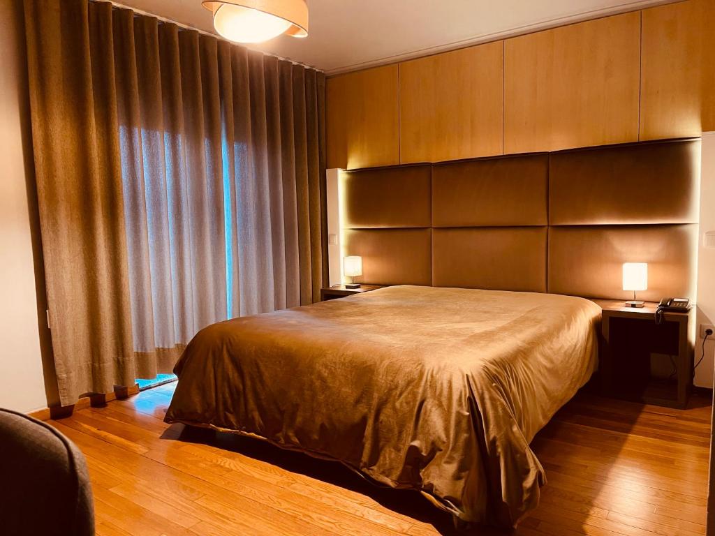 a bedroom with a large bed and two lamps at Hotel Europa in Vila Pouca de Aguiar
