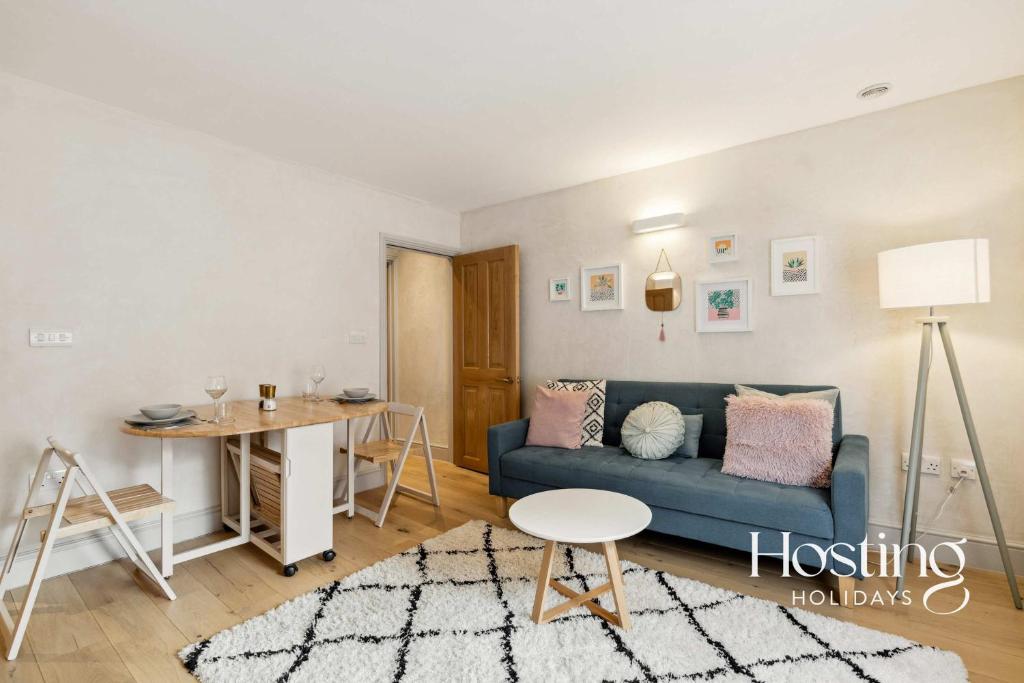a living room with a blue couch and a table at The Loft - 1 Bed Luxury Apartment with Bathtub in Henley on Thames