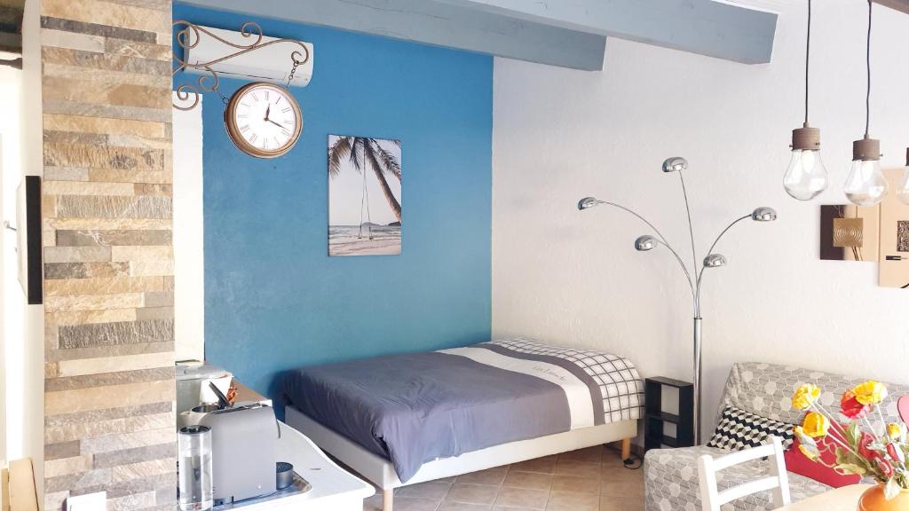une chambre avec un lit et une horloge au mur dans l'établissement studio 33 m2 au calme proche HYERES, à La Crau