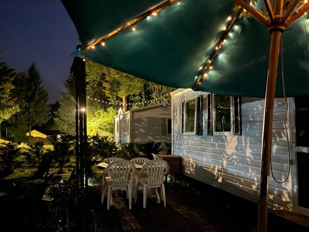 une table et des chaises sous un parapluie à côté d'une remorque dans l'établissement Mobil-Home avec belle exposition, à Saint-Chéron