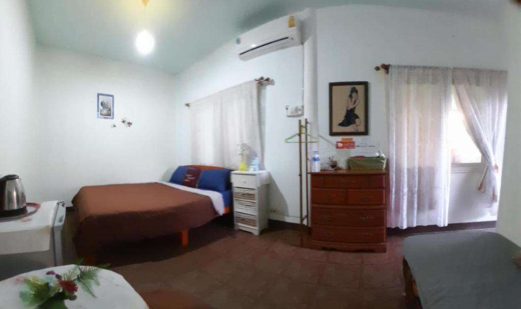 a bedroom with two beds and a dresser and a window at บ้านอังกาบ Aungkab homestay in Ban Muang Len