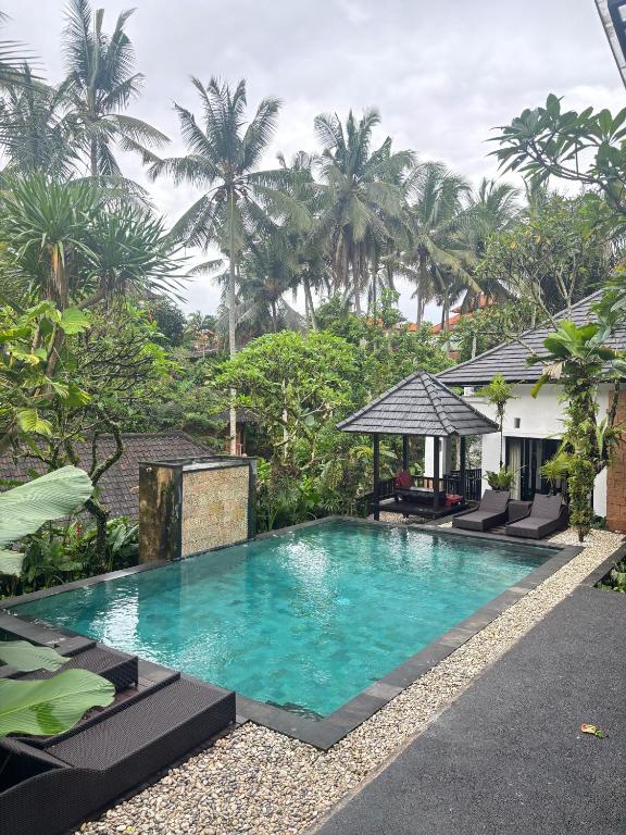a swimming pool in front of a house with palm trees at Igna Bungalows in Ubud