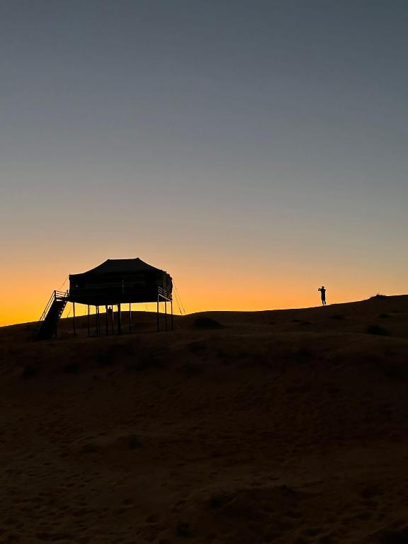 a person standing in the desert at sunset at Moon Light Camp in Bidiyah