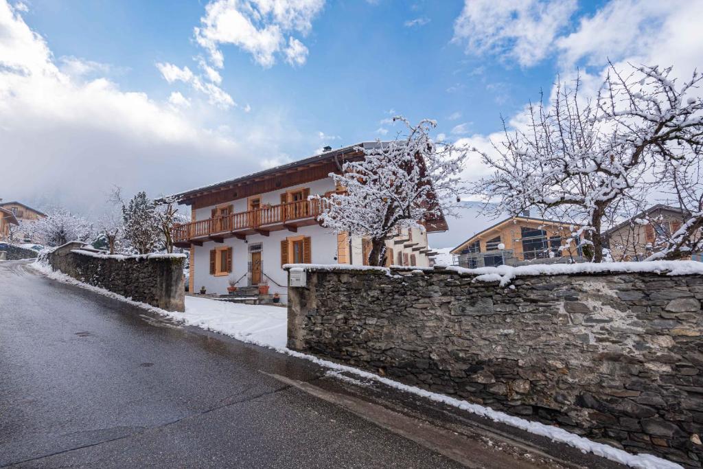 a stone wall and a house with snow on it at Maison Lennox in Mâcot La Plagne