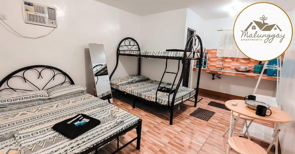 a room with two bunk beds and a table at Malunggay Apartments in Mariveles