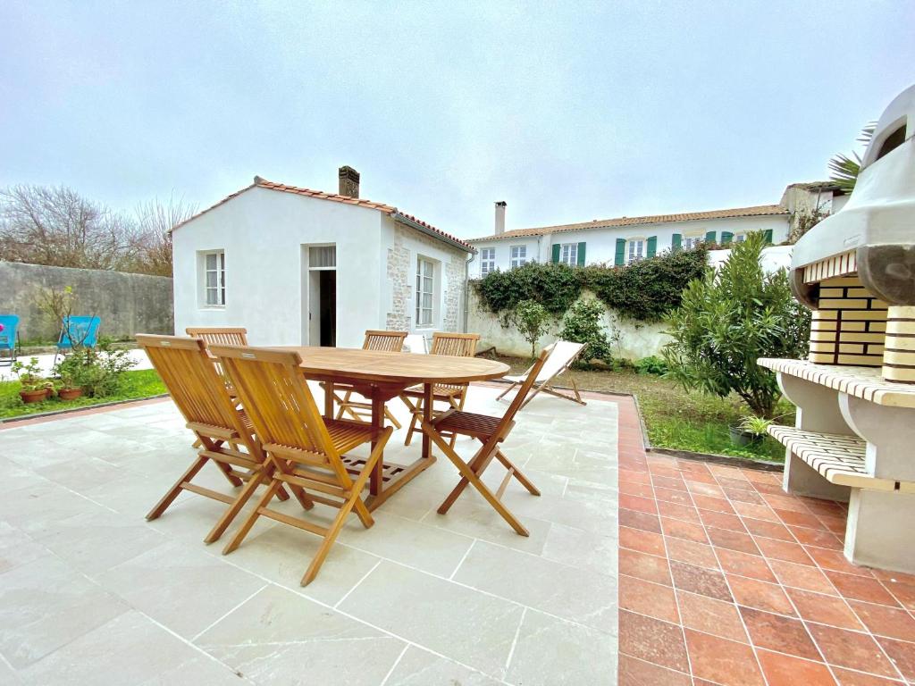 une table et des chaises en bois sur une terrasse dans l'établissement Les Volets Verts, au Bois-Plage-en-Ré