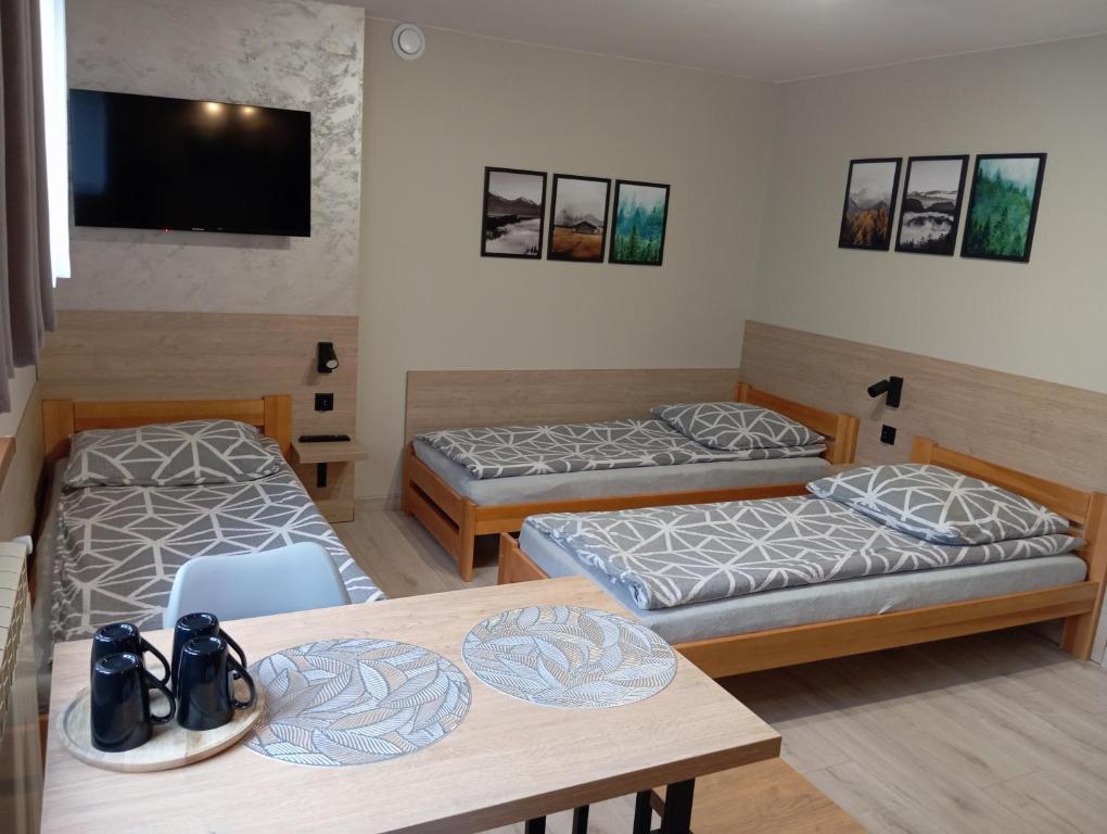a room with two beds and a table and a tv at Zacisze in Rozalin