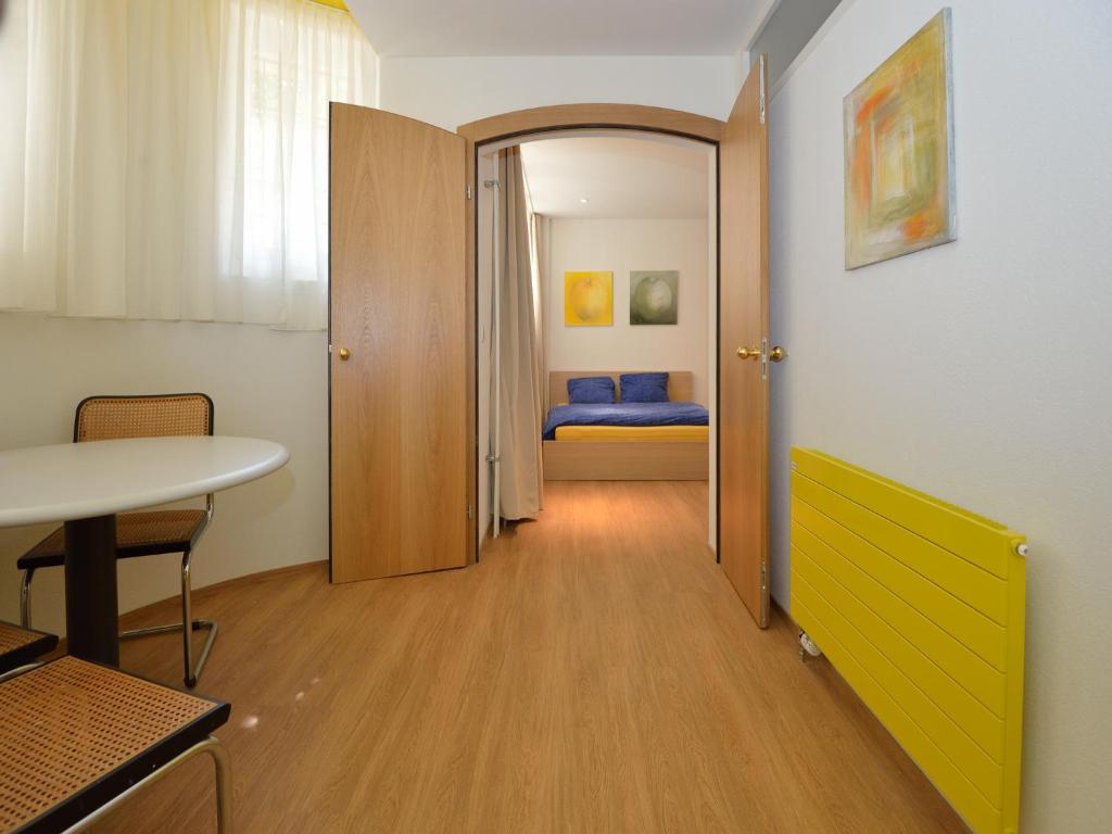 a hallway with a door to a room with a bed at Garden Studio Apartment Zürichberg in Zürich