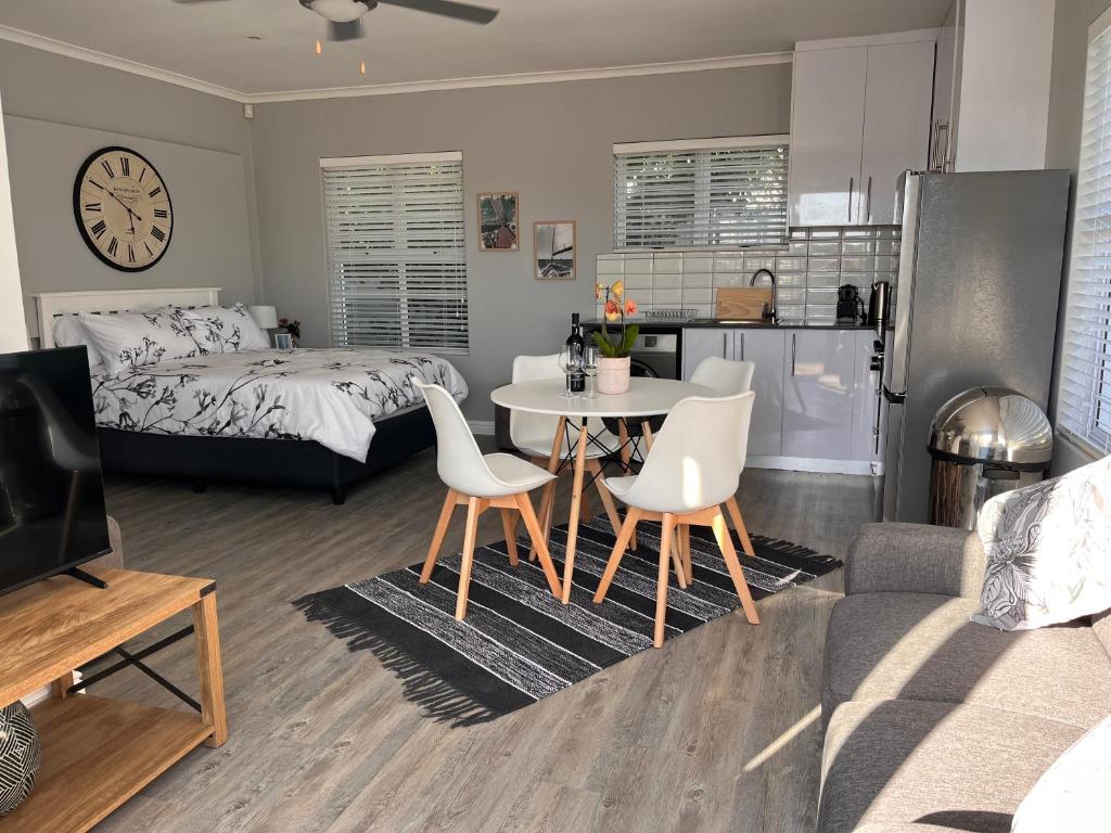 een woonkamer met een bed, een tafel en stoelen bij Cozy Cottage in Kaapstad