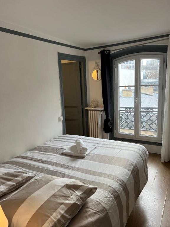 une chambre avec un lit et une grande fenêtre dans l'établissement Appartement proche Champs Élysée Paris 8e, à Paris