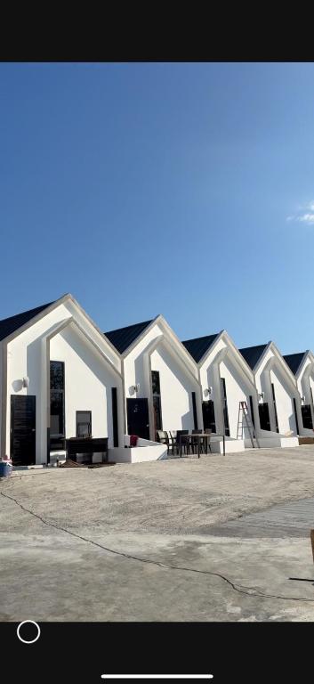 a row of white buildings with tables and chairs at PMEs Home in Ban Wang Kanhuat