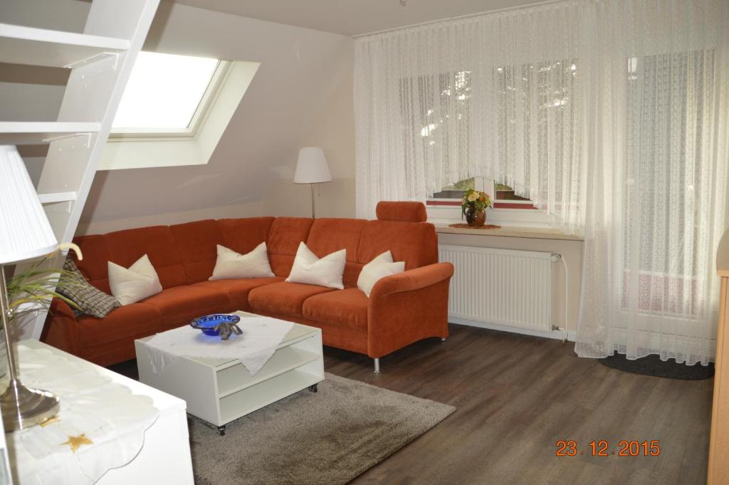 ノルトダイヒにあるFerienwohnungen Besslichのリビングルーム(オレンジ色のソファ、窓付)