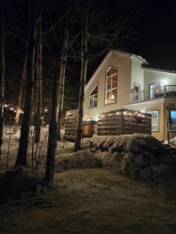 a house with lights in front of it at night at La Renardière des Monts in Les Éboulements