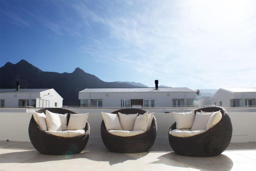 three chairs with pillows sitting on a patio at Spatalla Holiday Homes in Kleinmond