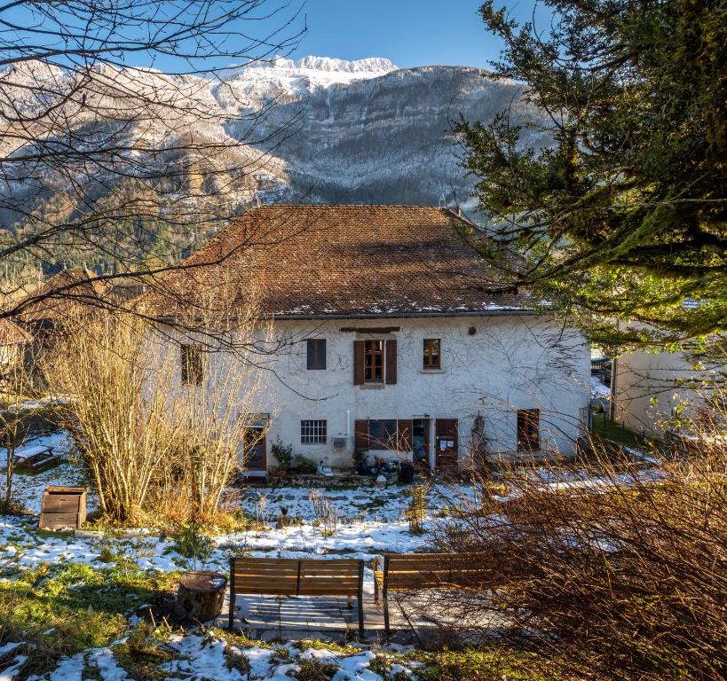 une maison blanche avec des montagnes en arrière-plan dans l'établissement Apt 1er étage - Gite aux 1000 chemins, à Saint-Joseph-de-Rivière