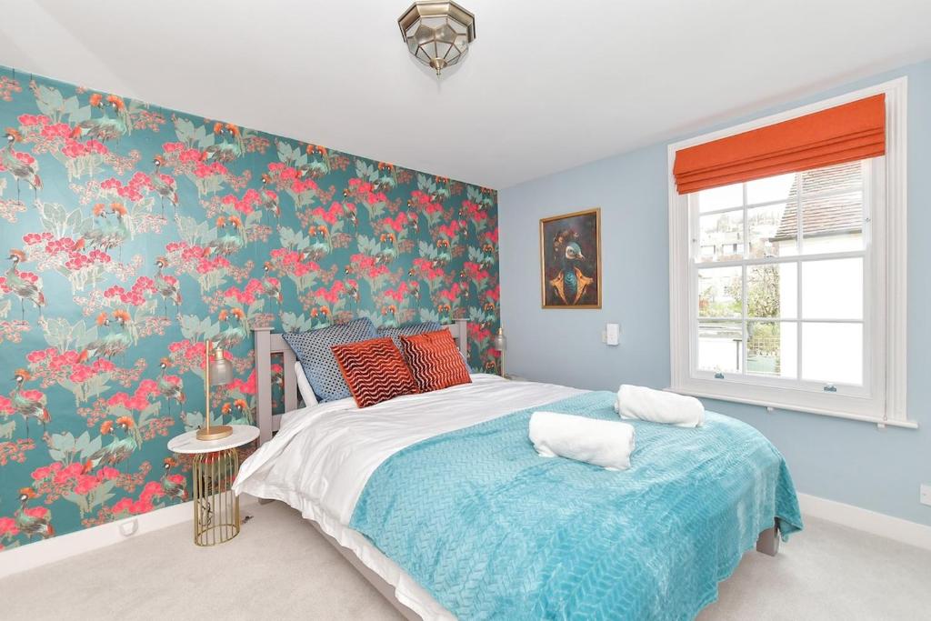 a bedroom with a bed with a floral wallpaper at Dove Cottage is a Central, Riverside, Charming Victorian Cottage in Arundel