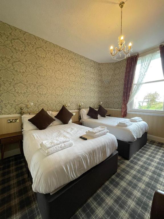 a hotel room with two beds and a chandelier at Headlands Hotel in Llandudno