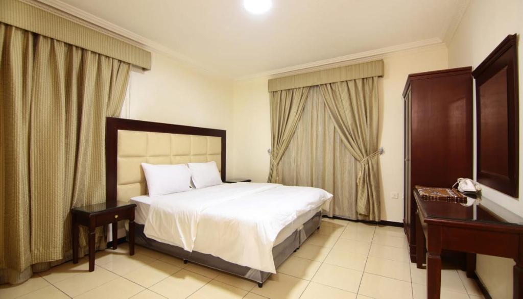 a bedroom with a bed and two tables and a window at Jumeirah in Jeddah