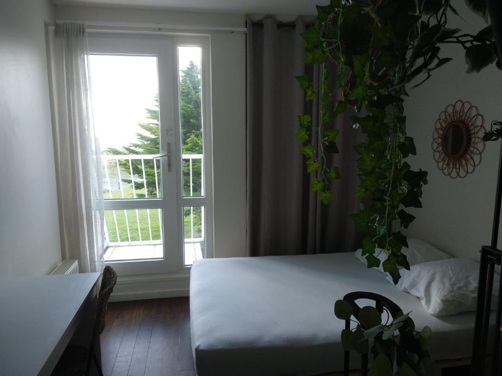 sypialnia z łóżkiem i dużym oknem w obiekcie Charmant logement Guidel Plage, chambre vue mer, piscine chauffée w mieście Guidel