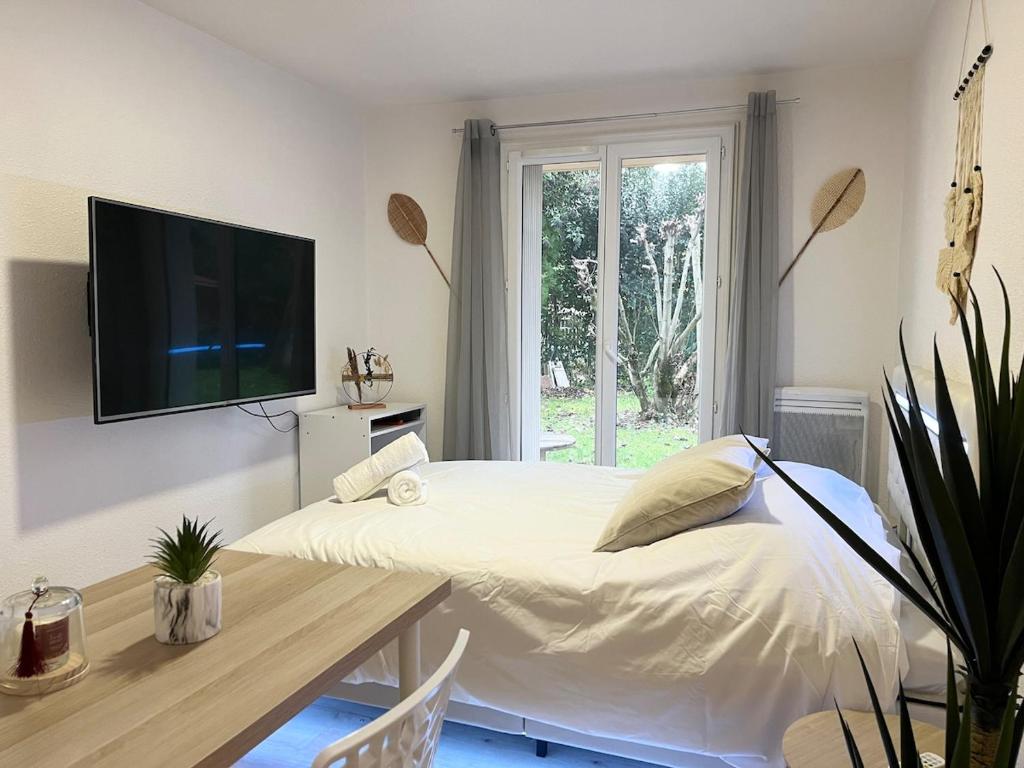 une chambre avec un lit, une table et une télévision dans l'établissement Le nid du busca proche métro, à Toulouse