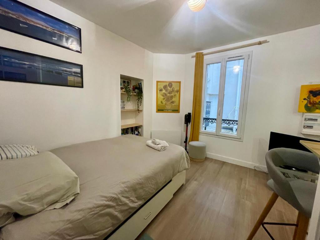 une chambre avec un lit, un bureau et une fenêtre dans l'établissement VANVES studio calme rez-de-chaussée cour Porte de Versailles, à Vanves