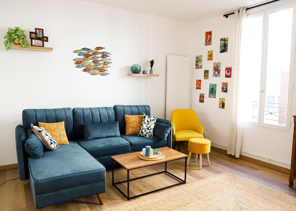 un salon avec un canapé bleu et un fauteuil jaune dans l'établissement Le Petit Parisien, au Kremlin-Bicêtre