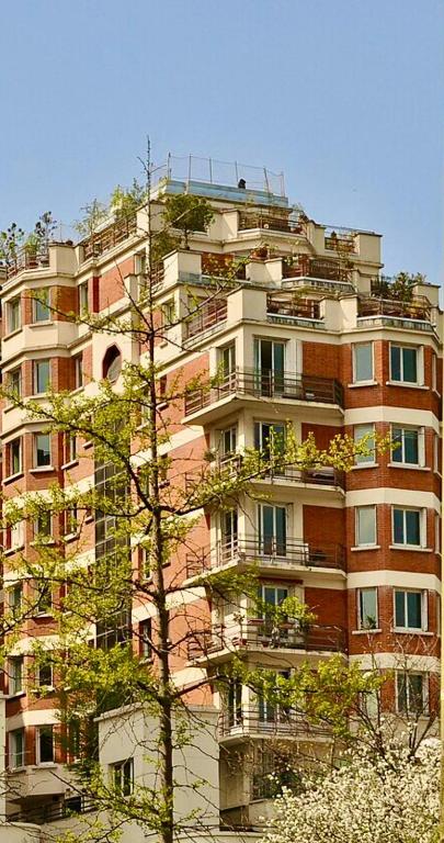 un grand bâtiment avec un arbre devant lui dans l'établissement Appartement cosy proximité gare de Saint Cloud, à Saint-Cloud