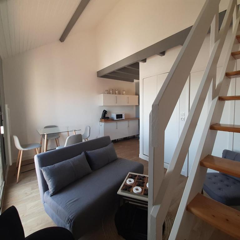 un salon avec un canapé et un escalier dans l'établissement appartement calme et lumineux , centre ville et plage à pied, à Pornichet