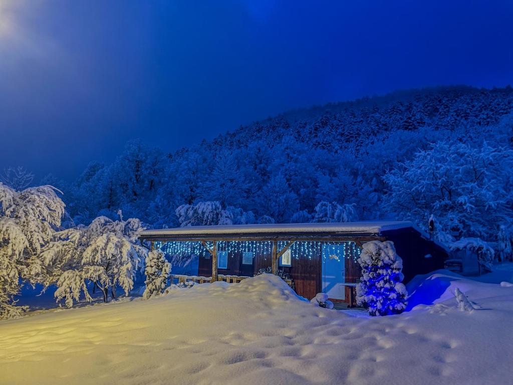 a house covered in snow at night with christmas lights at Home La Sierra with WHIRLPOOL BATH for two in Korenica