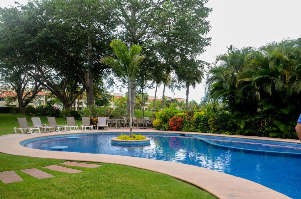 a swimming pool with a fountain in the middle of a yard at El Tigre, Green Bay I Shared Pool in Nuevo Vallarta 