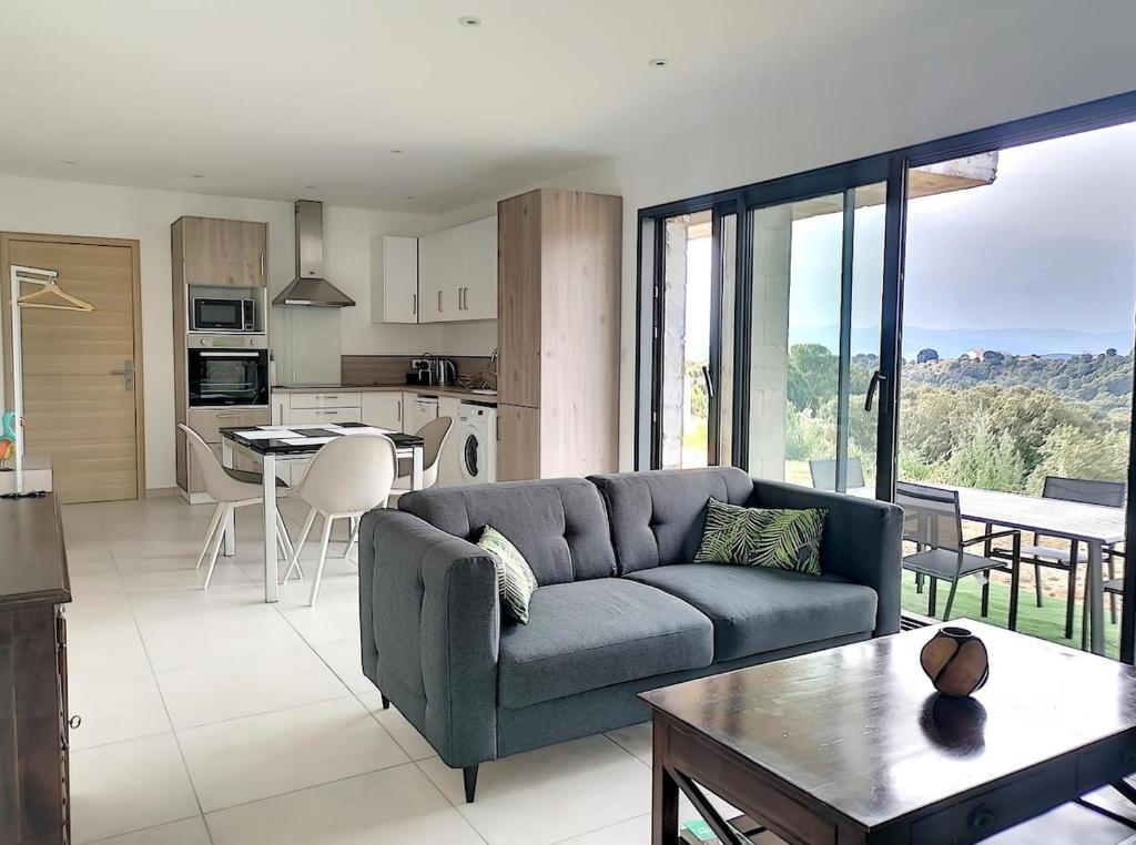 un salon avec un canapé bleu et une cuisine dans l'établissement Bas de villa contemporaine avec vue dégagée, à Alata