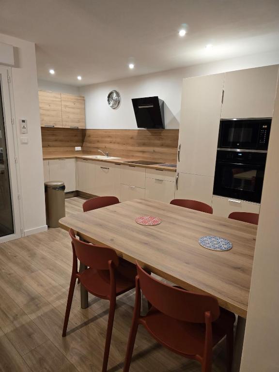 une cuisine avec une table en bois et quelques chaises dans l'établissement Appartement cosy près de Sceneo et Auchan au dessus du fleuriste Bellafleur, à Longuenesse