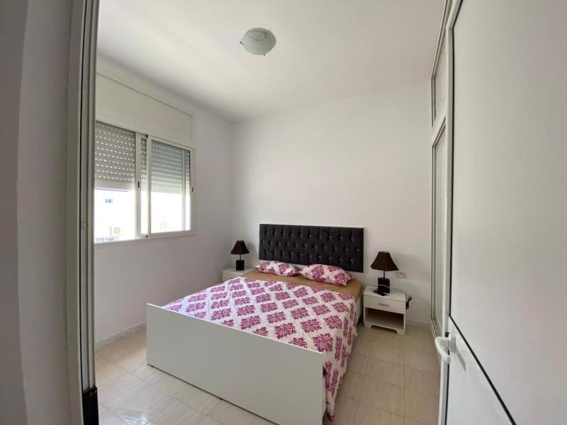a white bedroom with a bed with a pink blanket at samia fekih in El Hafsi