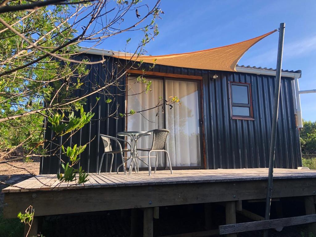 a tiny house with a table and chairs on a deck at Casetta del Acqua - Eco Off-Grid Fynbos Cottage in Plettenbergbaai