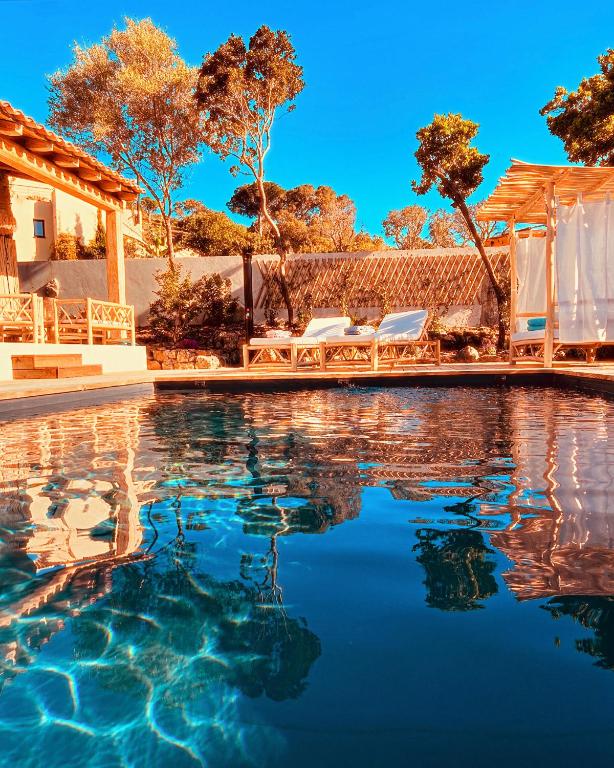 une piscine avec deux chaises et une maison dans l'établissement Bergerie U'caseddu, à Cirendinu