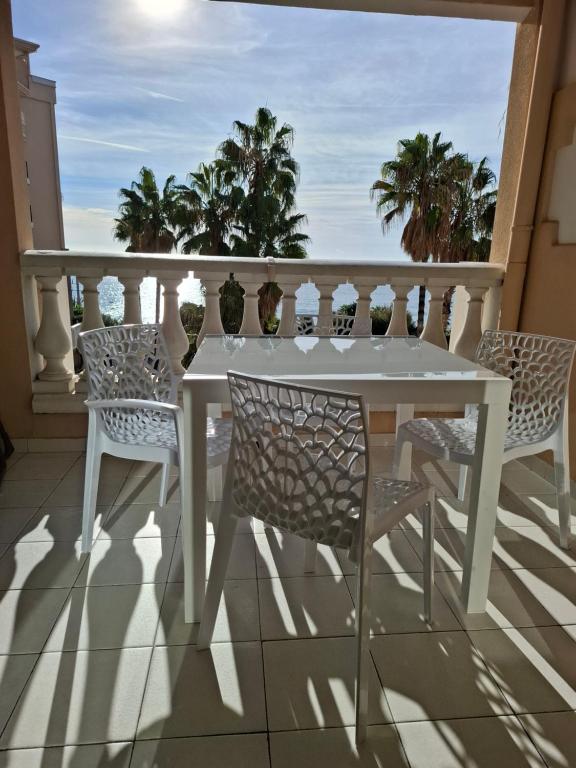 une table blanche et des chaises sur un balcon avec l'océan dans l'établissement Cap ô sud 1, à Cannes